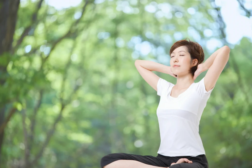木漏れ日の中でゆっくり呼吸する女性